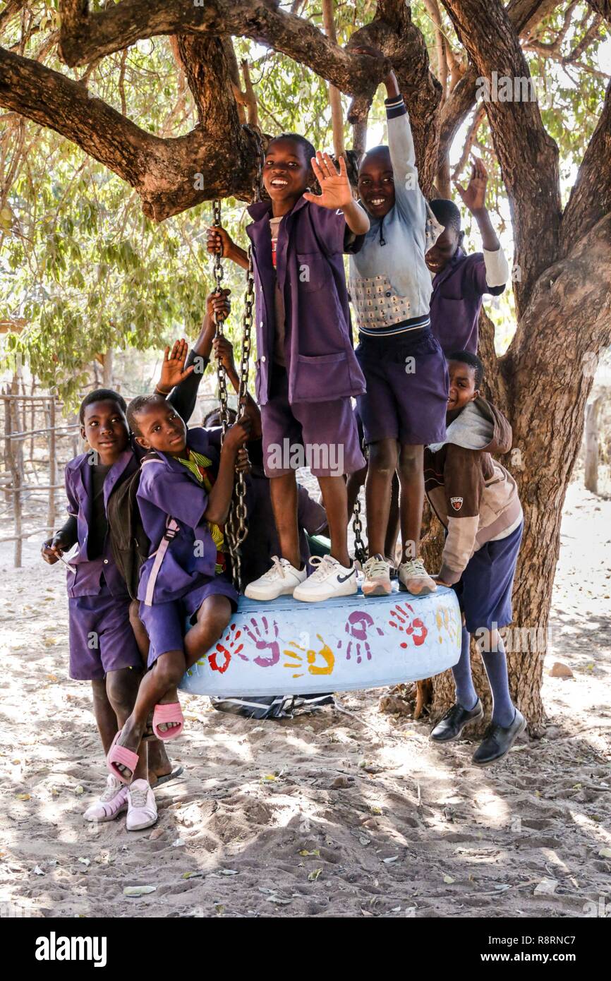 African schoolboys on tyre swing smiling, Kariba South Primary School, Zambia Stock Photo