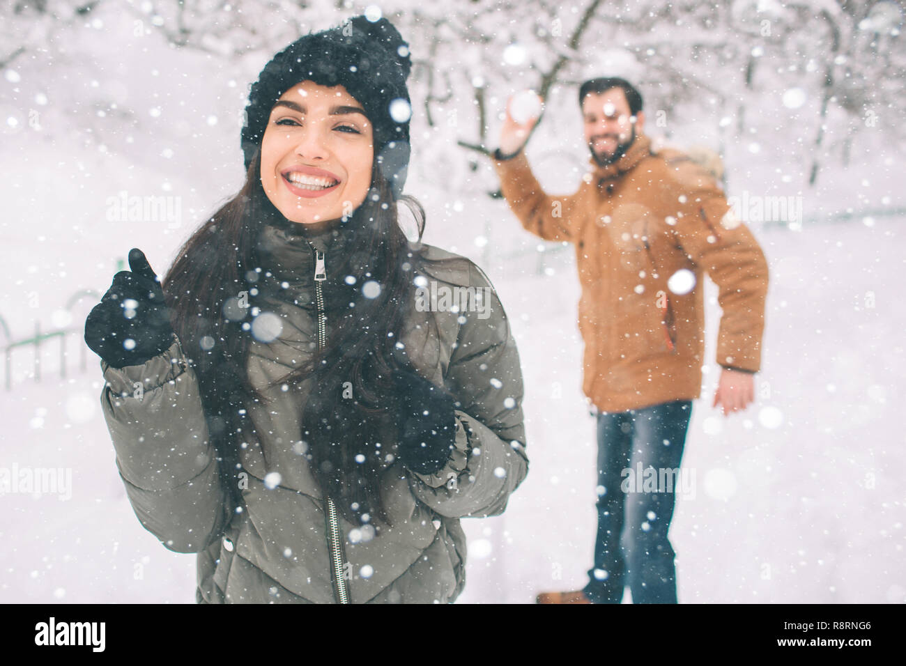 Happy Young Couple in Winter . Family Outdoors. man and woman looking  upwards and laughing. Love, fun, season and people - walking in winter  park. He is snowballing Stock Photo - Alamy