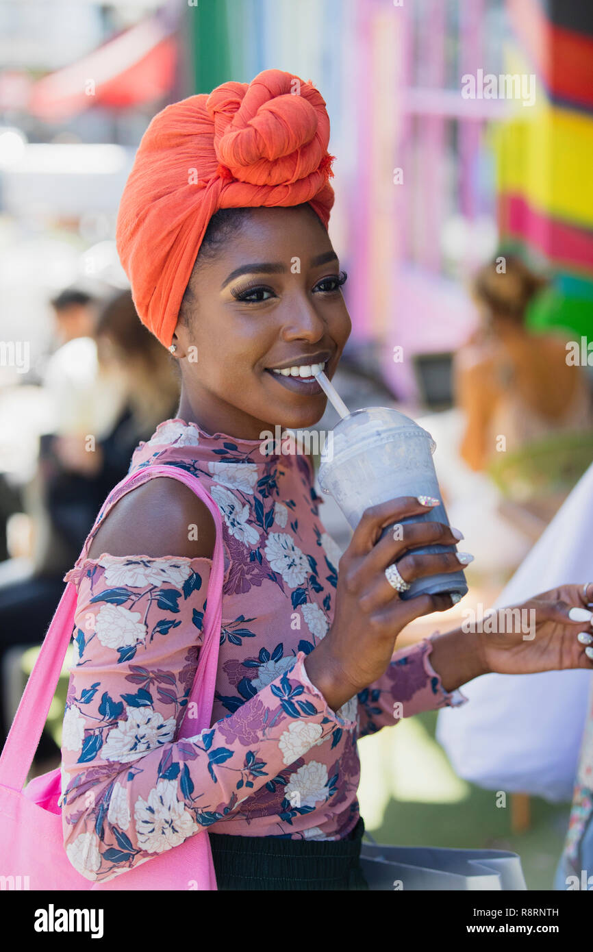 Smiling young woman in headscarf drinking smoothie Stock Photo
