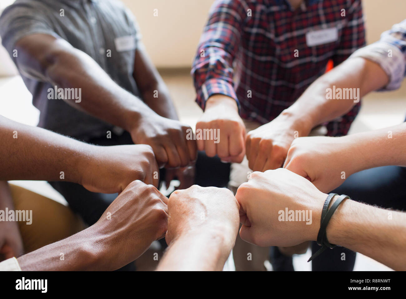 Men joining fists in circle in group therapy Stock Photo