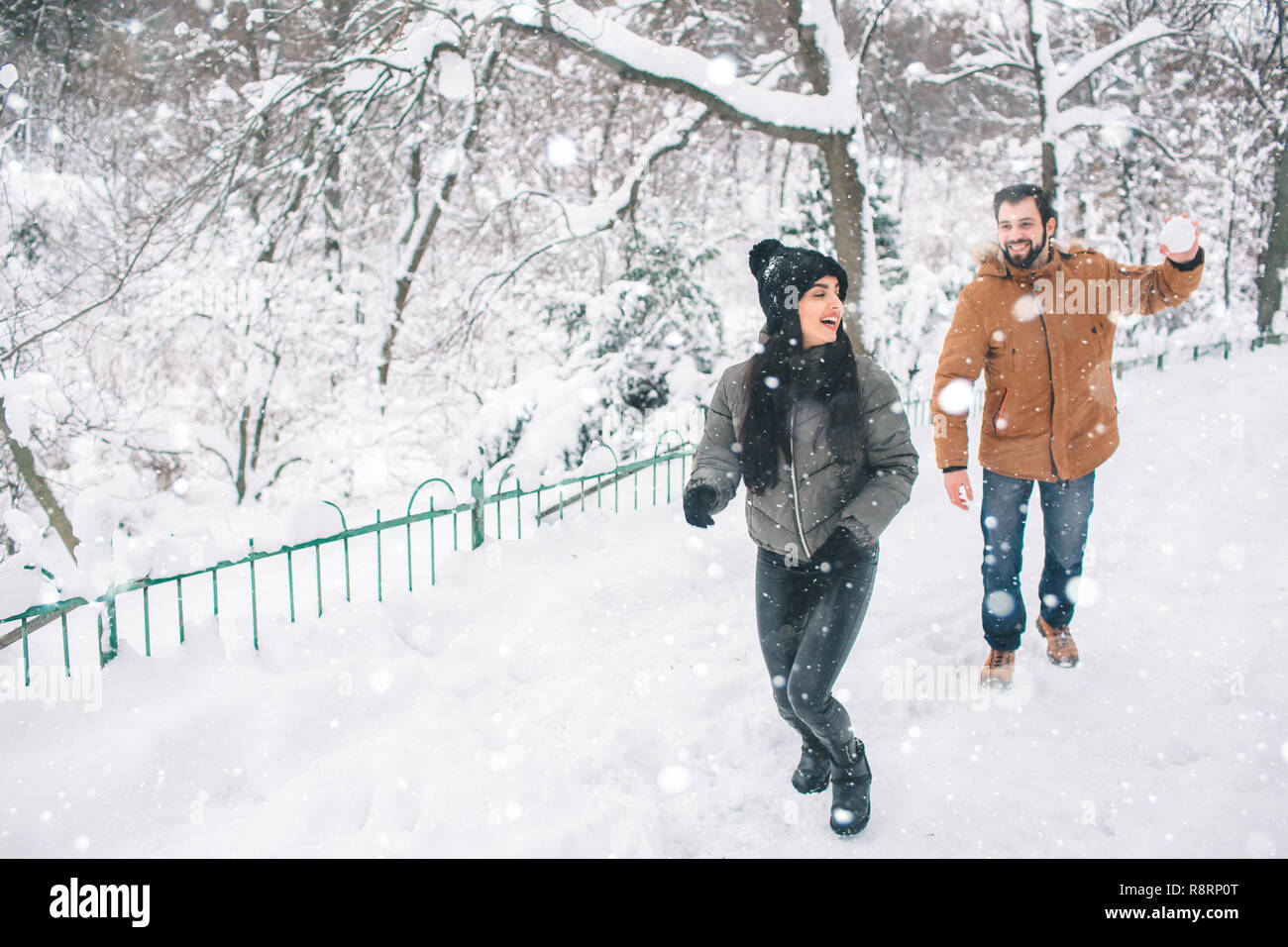 Happy Young Couple in Winter . Family Outdoors. man and woman looking  upwards and laughing. Love, fun, season and people - walking in winter  park. He is snowballing Stock Photo - Alamy