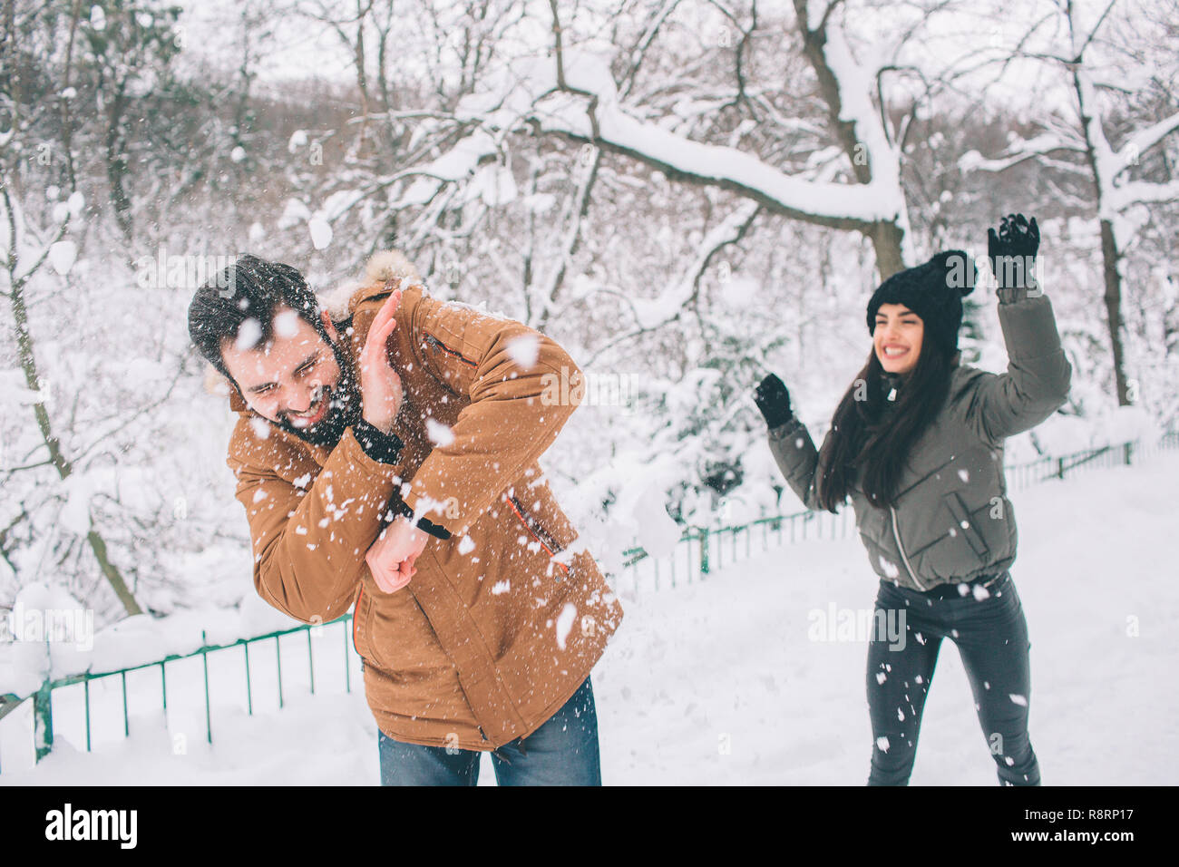 Happy Young Couple in Winter . Family Outdoors. man and woman looking  upwards and laughing. Love, fun, season and people - walking in winter  park. He is snowballing Stock Photo - Alamy