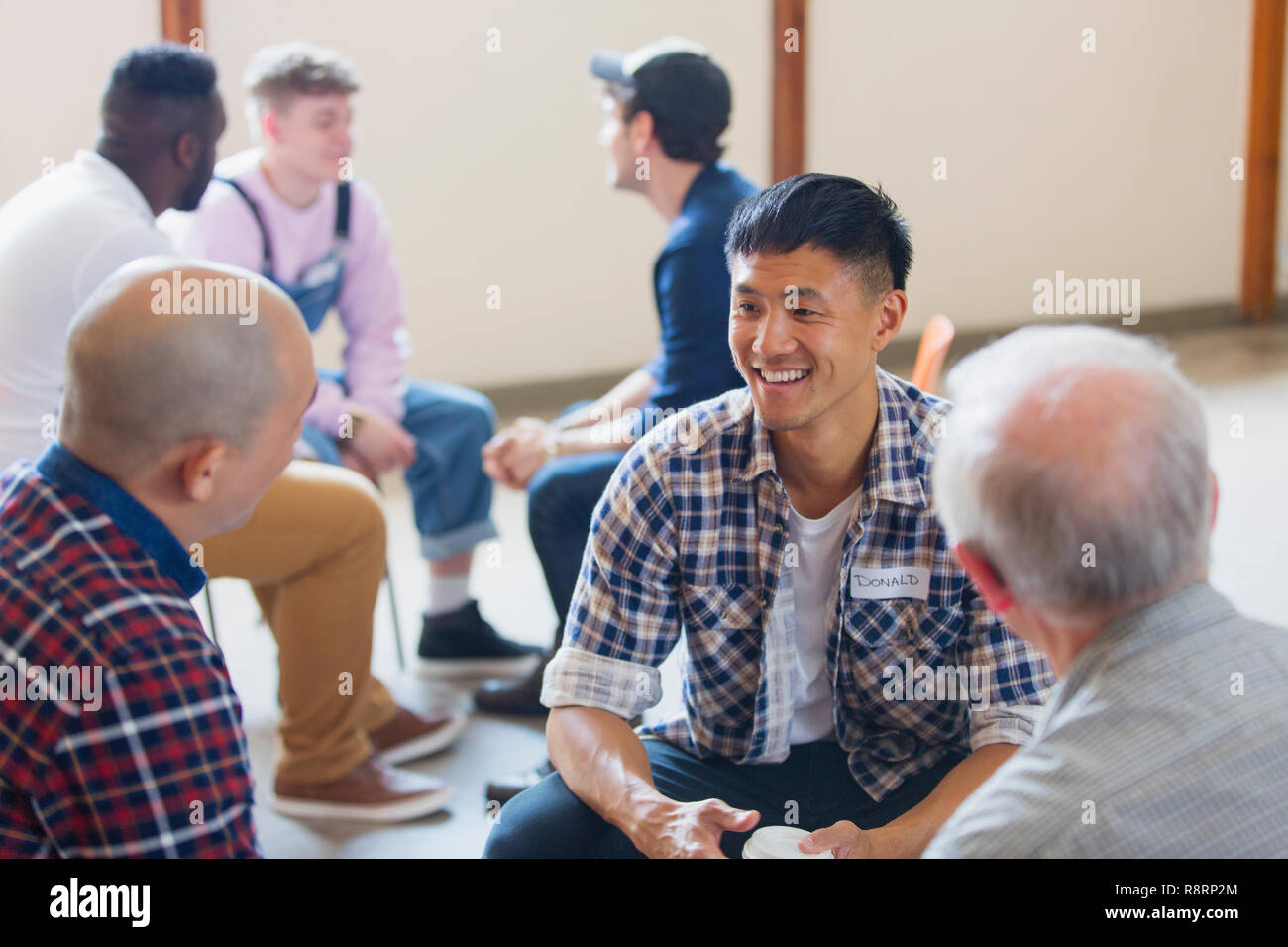 Men talking and listening in group therapy Stock Photo