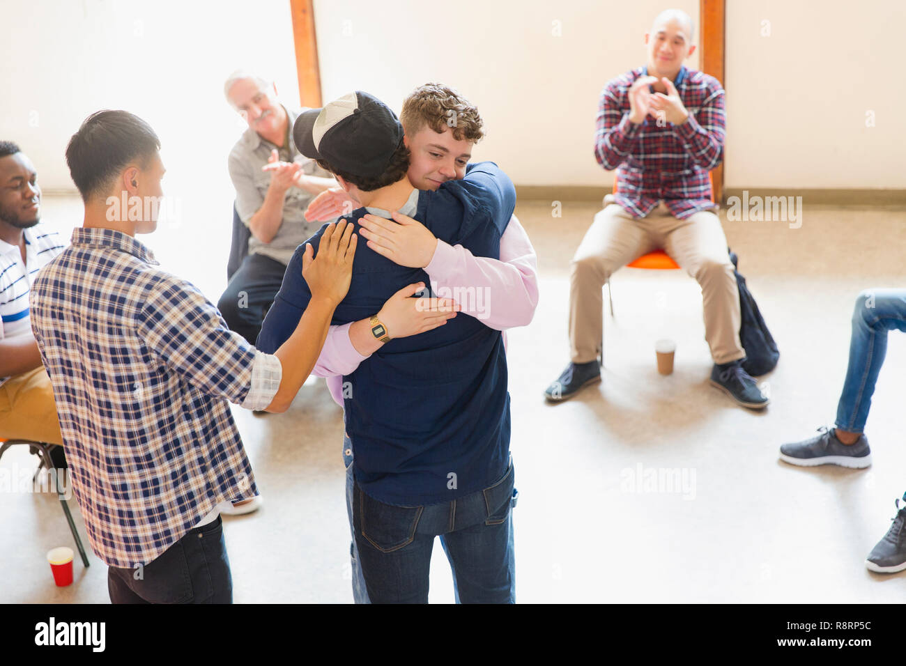 Men hugging and clapping in group therapy Stock Photo
