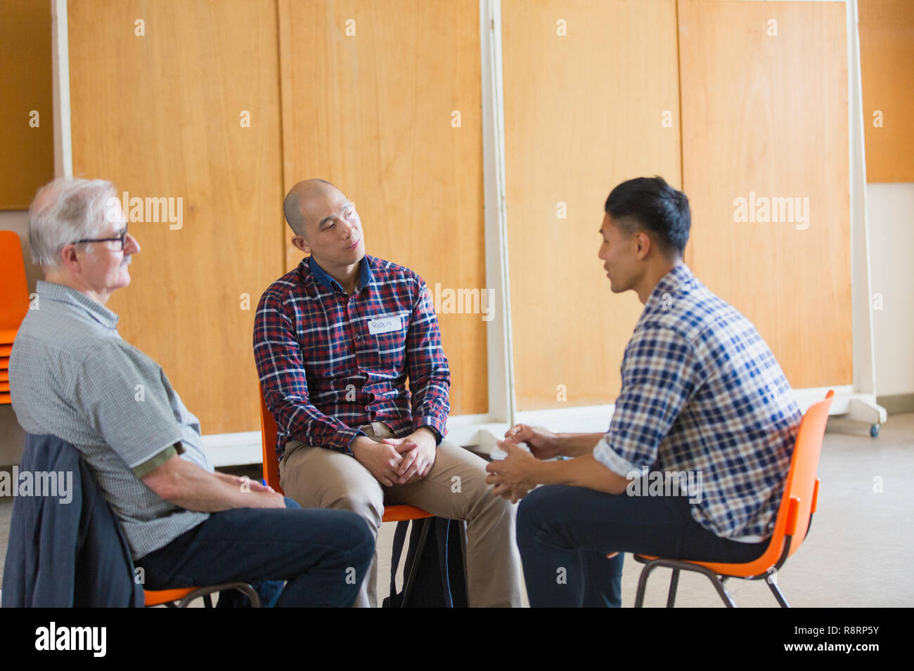 Men talking and listening in group therapy Stock Photo