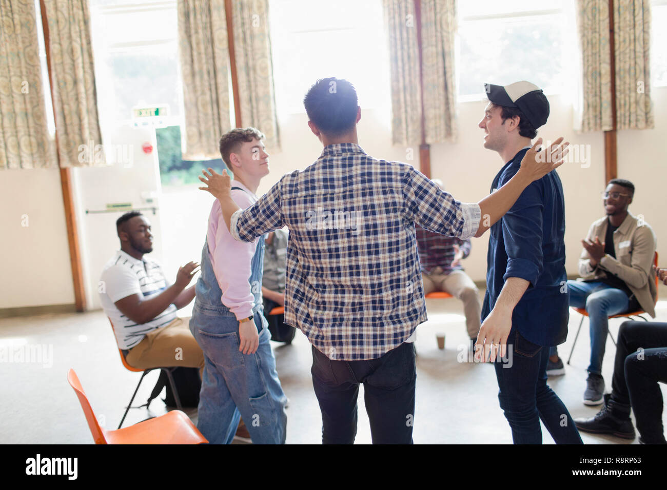 Men talking and clapping in group therapy in community center Stock Photo