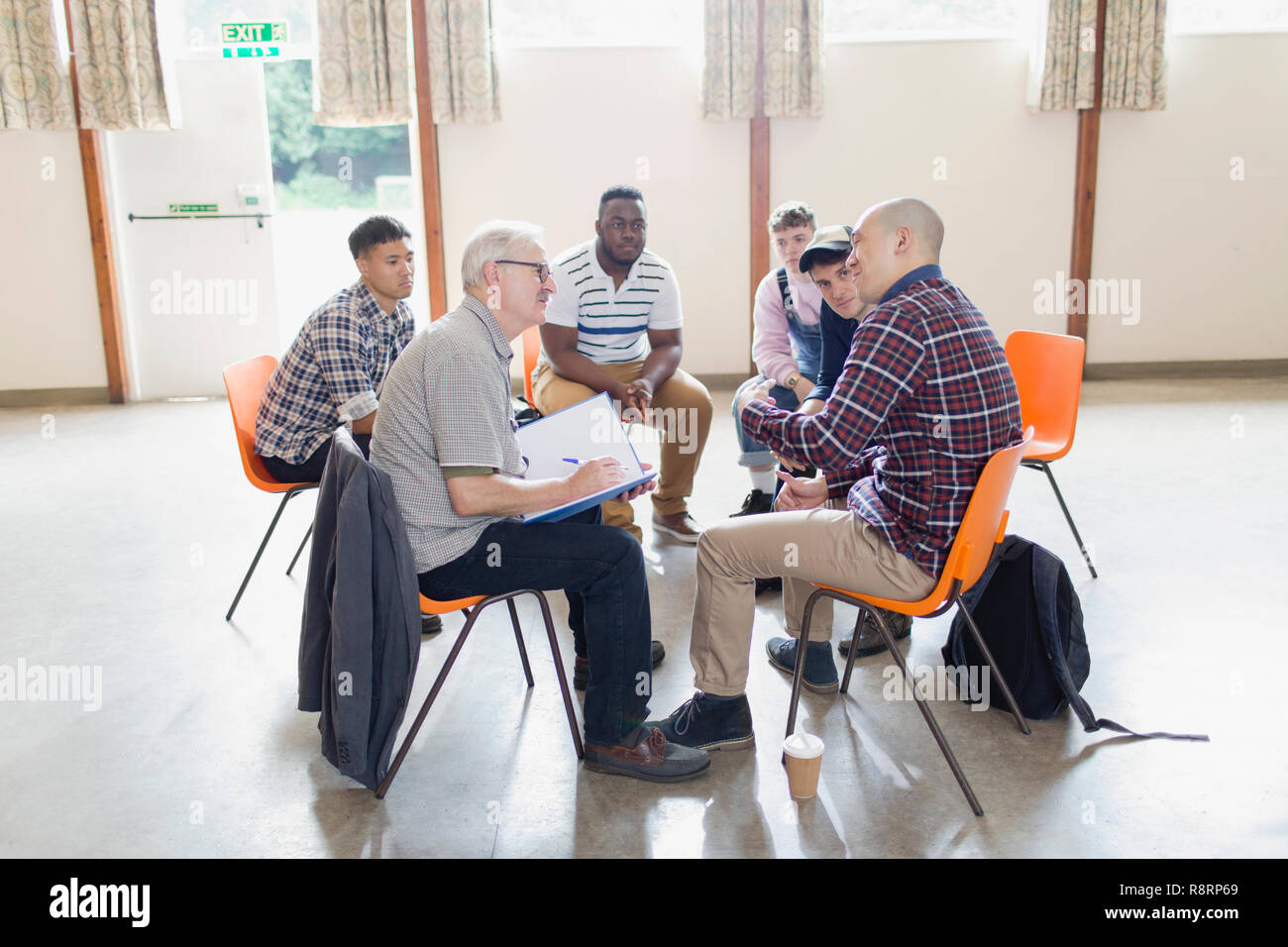 Men talking in circle in group therapy Stock Photo