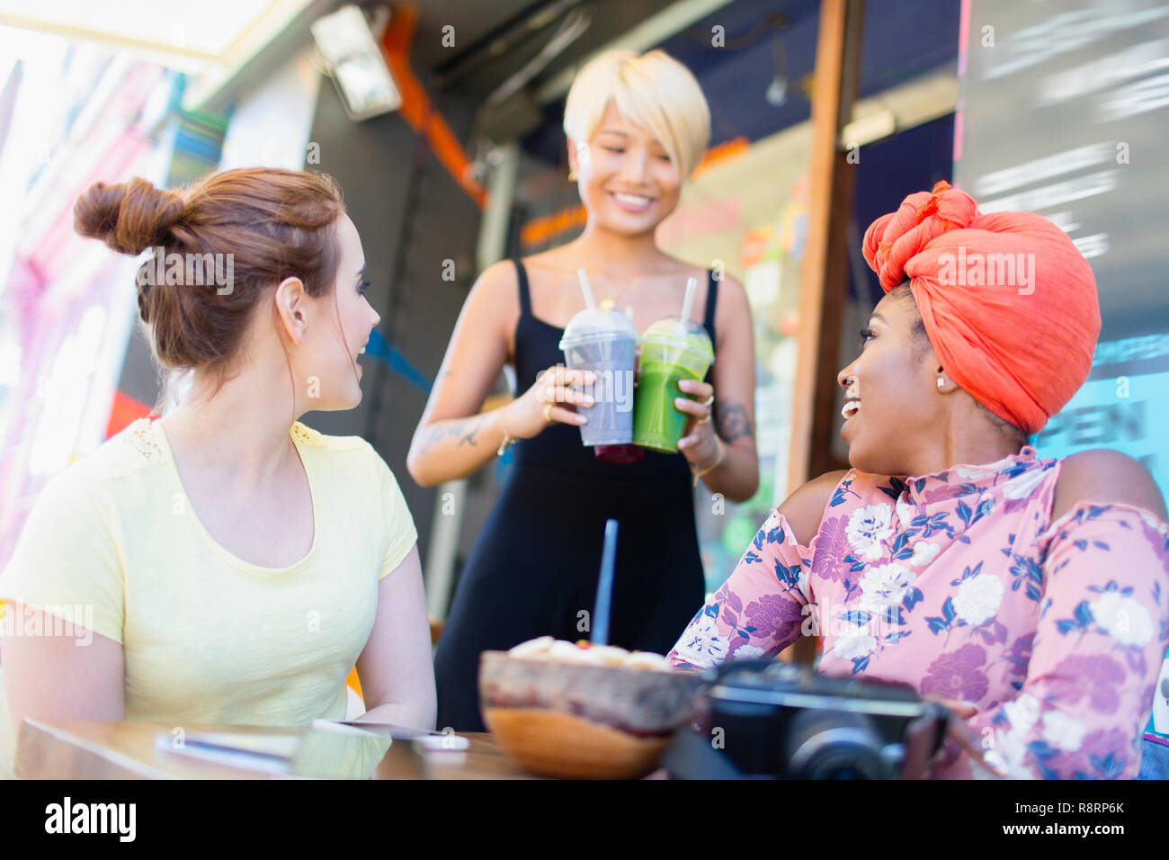 Waitress serving smoothies to women friends at sidewalk cafe Stock Photo