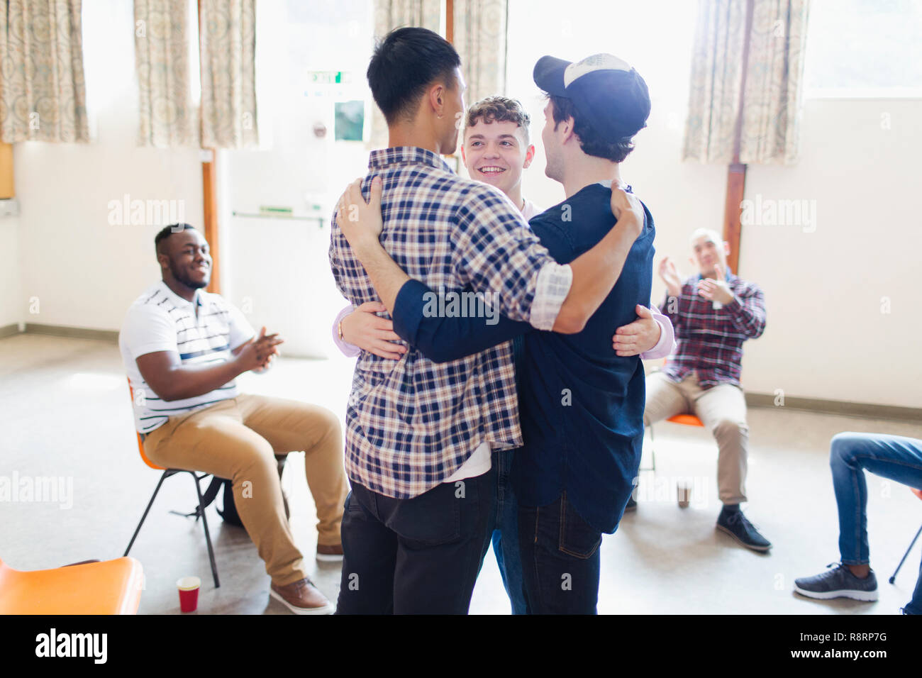 Men hugging in group therapy Stock Photo