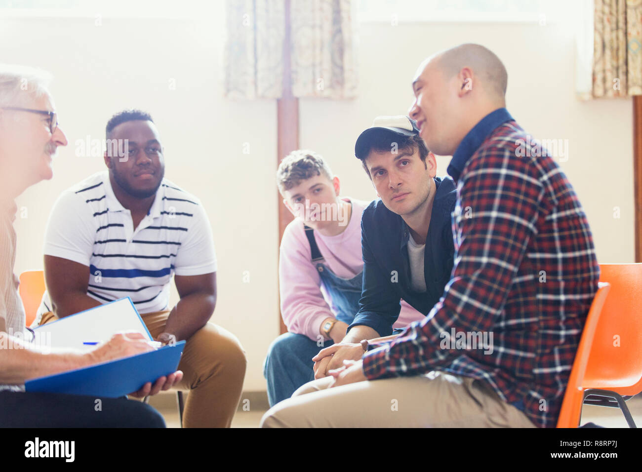 Attentive men talking and listening in group therapy Stock Photo