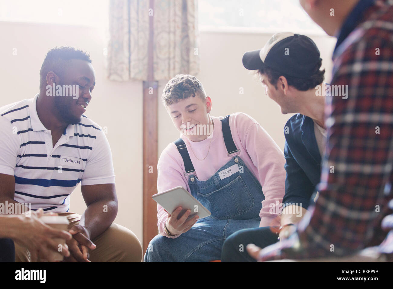 Men with digital tablet talking in group therapy Stock Photo