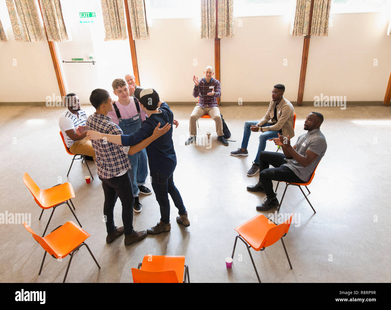 Men hugging and clapping in group therapy Stock Photo