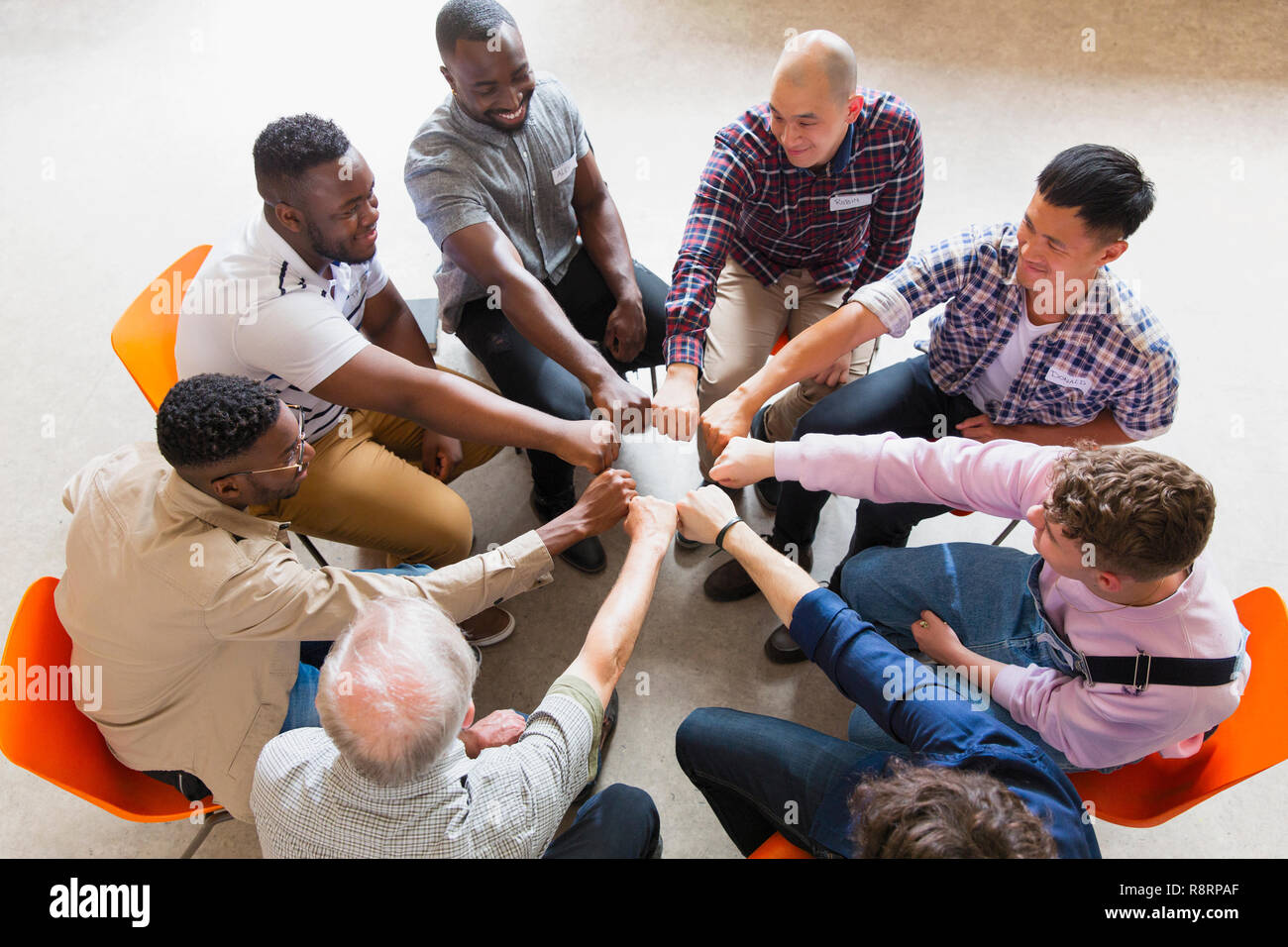 Men joining fists in circle in group therapy Stock Photo