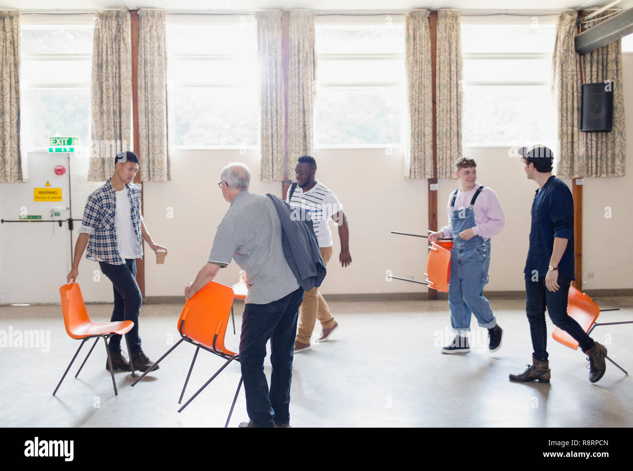 Men arranging chairs for group therapy in community center Stock Photo