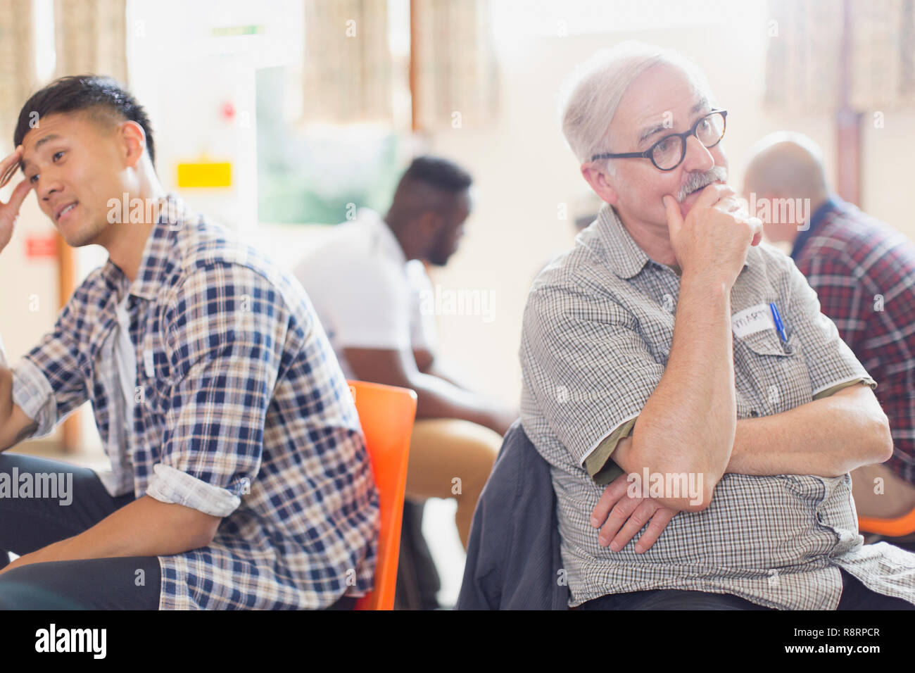Men talking and listening in group therapy in community center Stock Photo