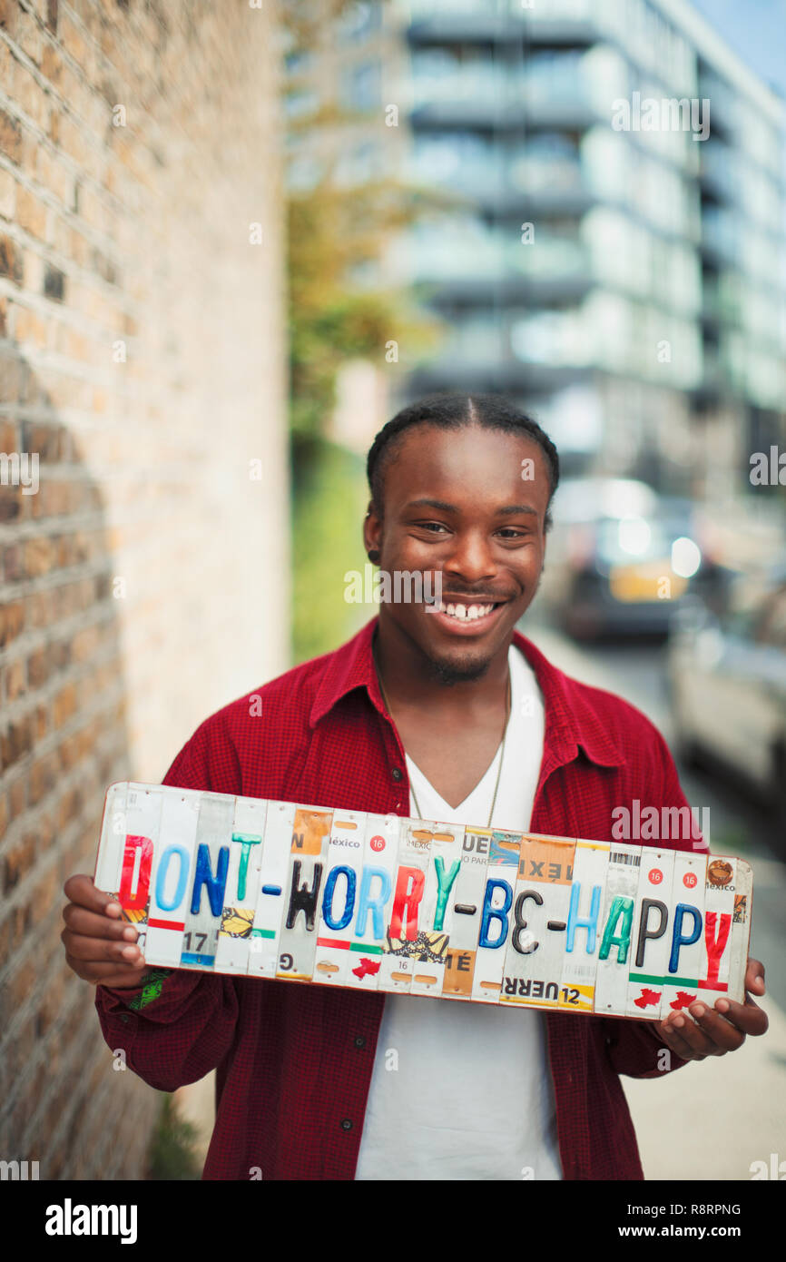 Portrait smiling teenage boy holding  Dont Worry Be Happy  license plates Stock Photo