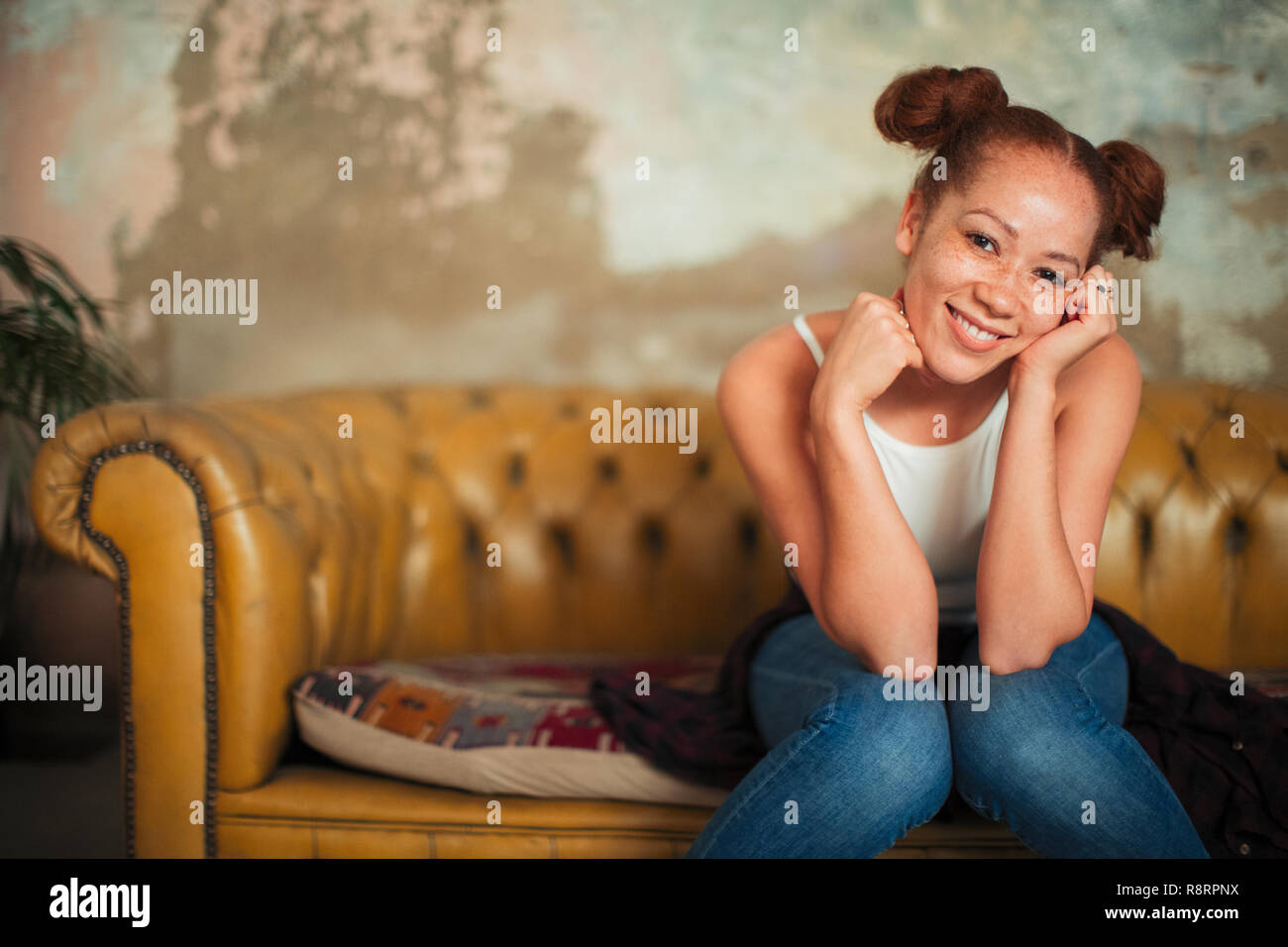 Portrait smiling, confident young woman sitting on sofa Stock Photo