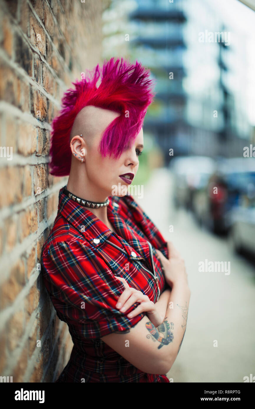 Confident young woman with pink mohawk on urban sidewalk Stock Photo