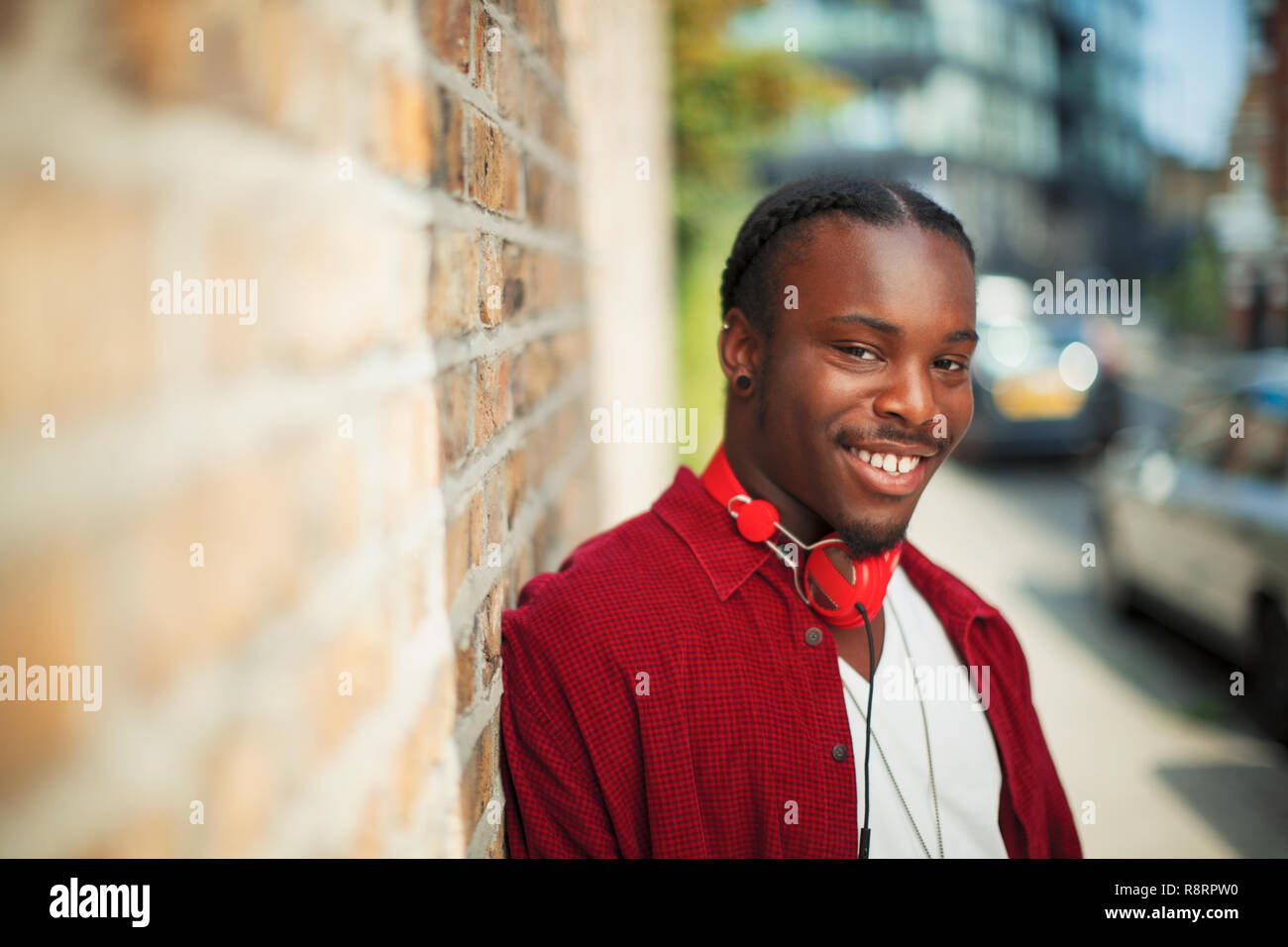 Portrait smiling, confident teenage boy with headphones on urban sidewalk Stock Photo