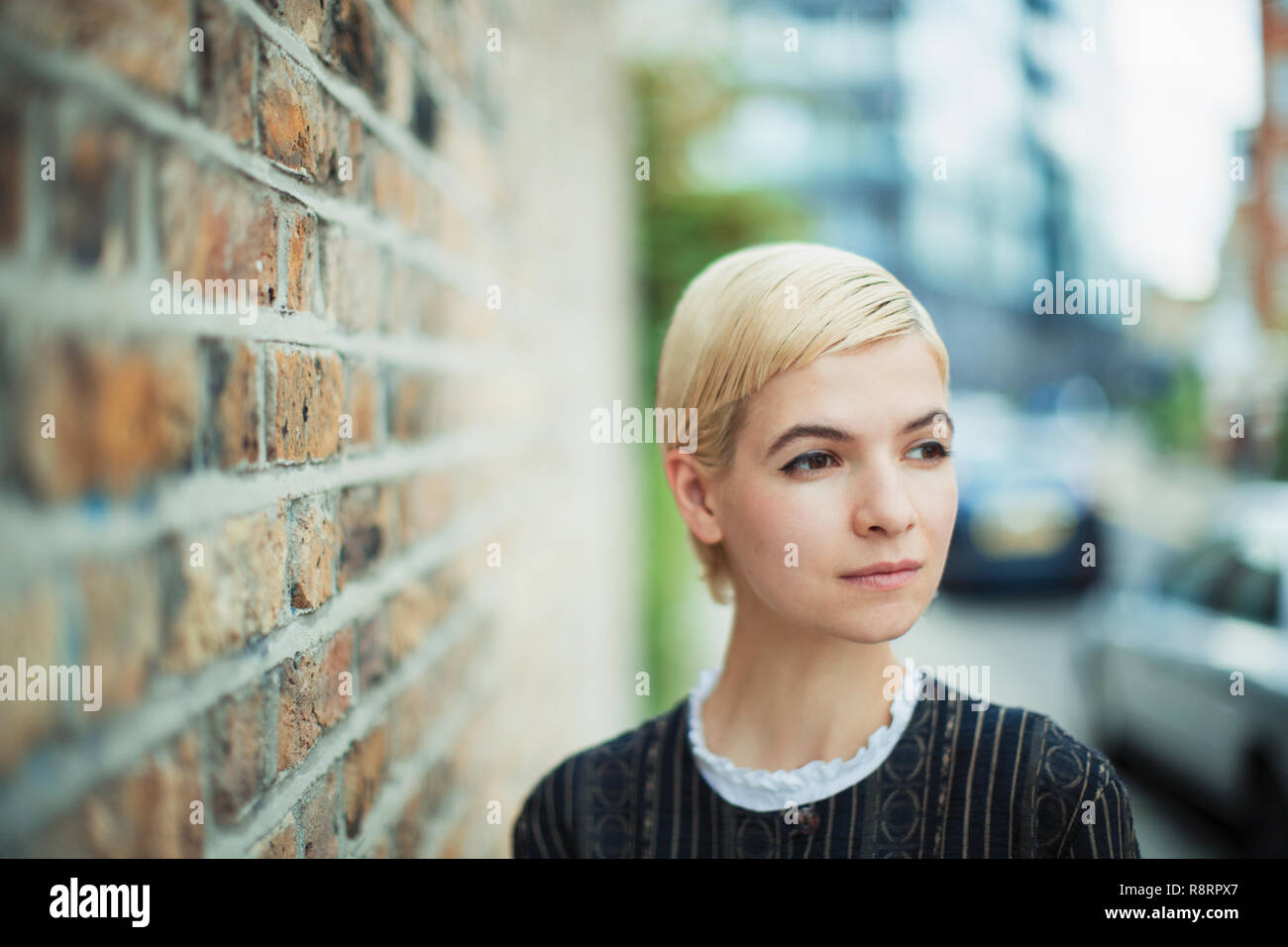 Serene young woman looking away on urban sidewalk Stock Photo