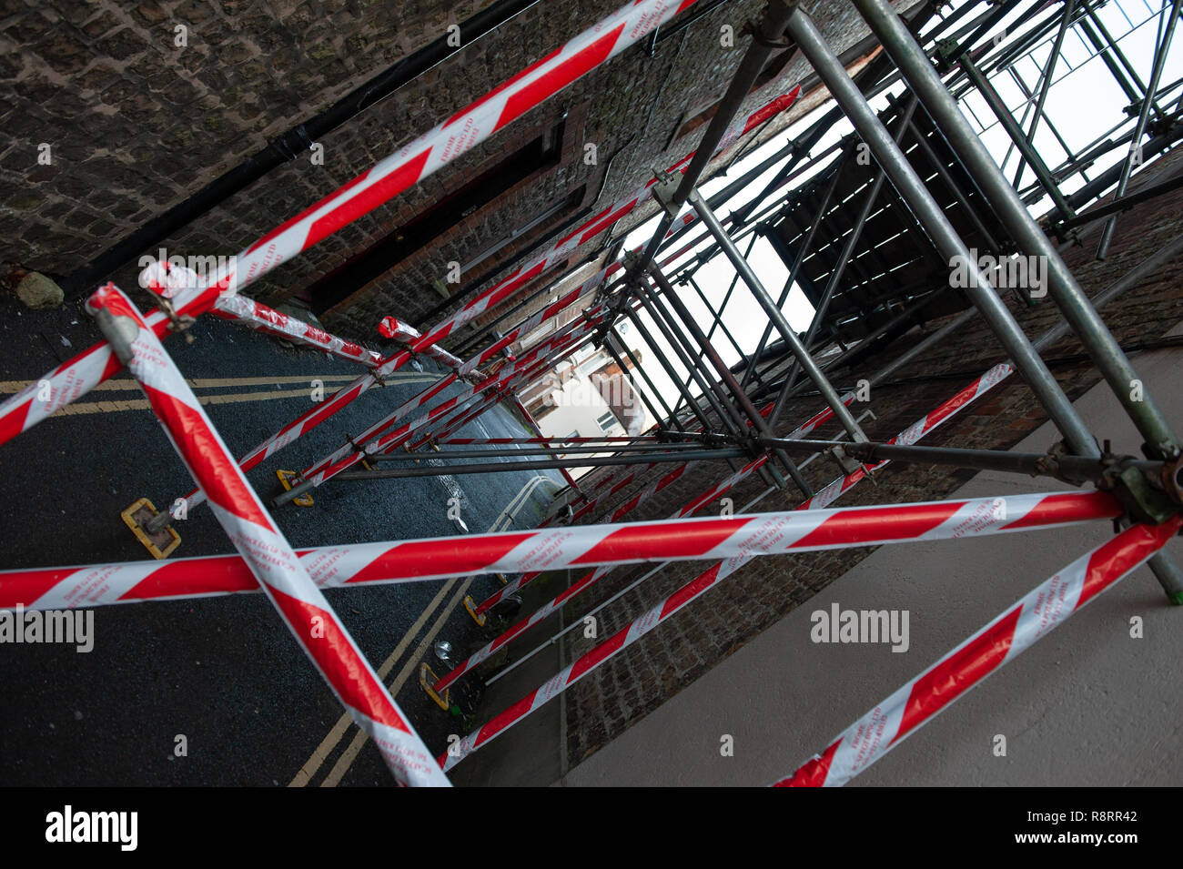 Scaffolding with warning tape attached in narrow lane at Warminster, Wiltshire, UK. Stock Photo