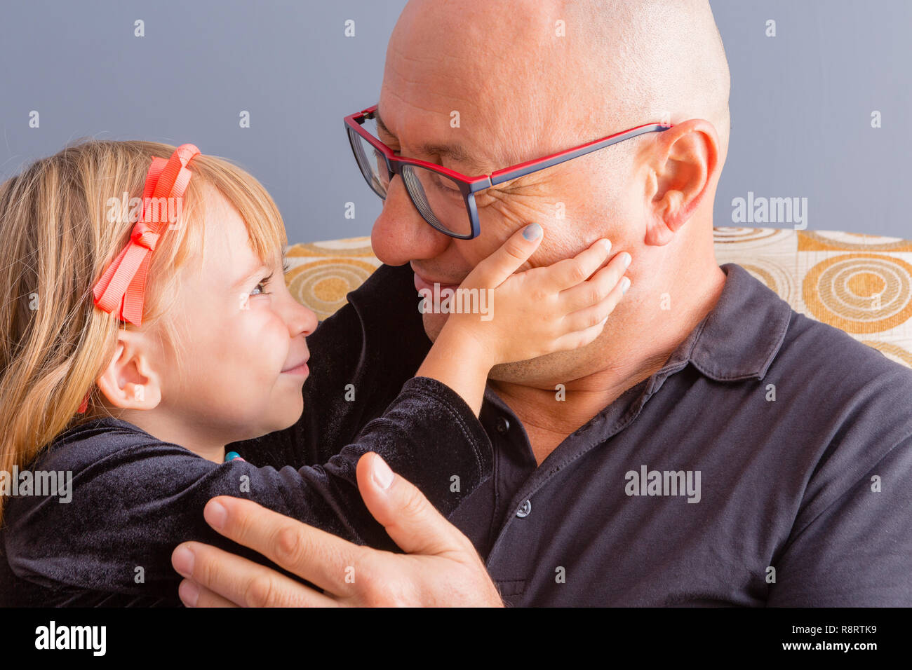 Loving father and daughter share a tender moment as the little girl caresses her Daddy on the cheeks with a beautiful smile in a close up cropped port Stock Photo