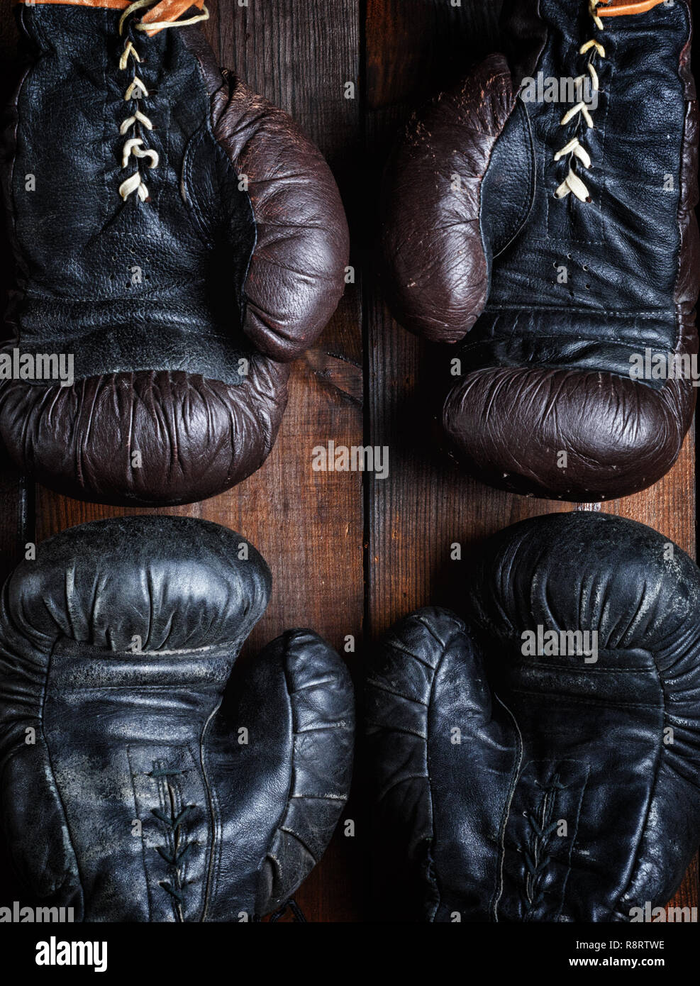 two pairs of leather old boxing gloves on wooden background, top view Stock Photo