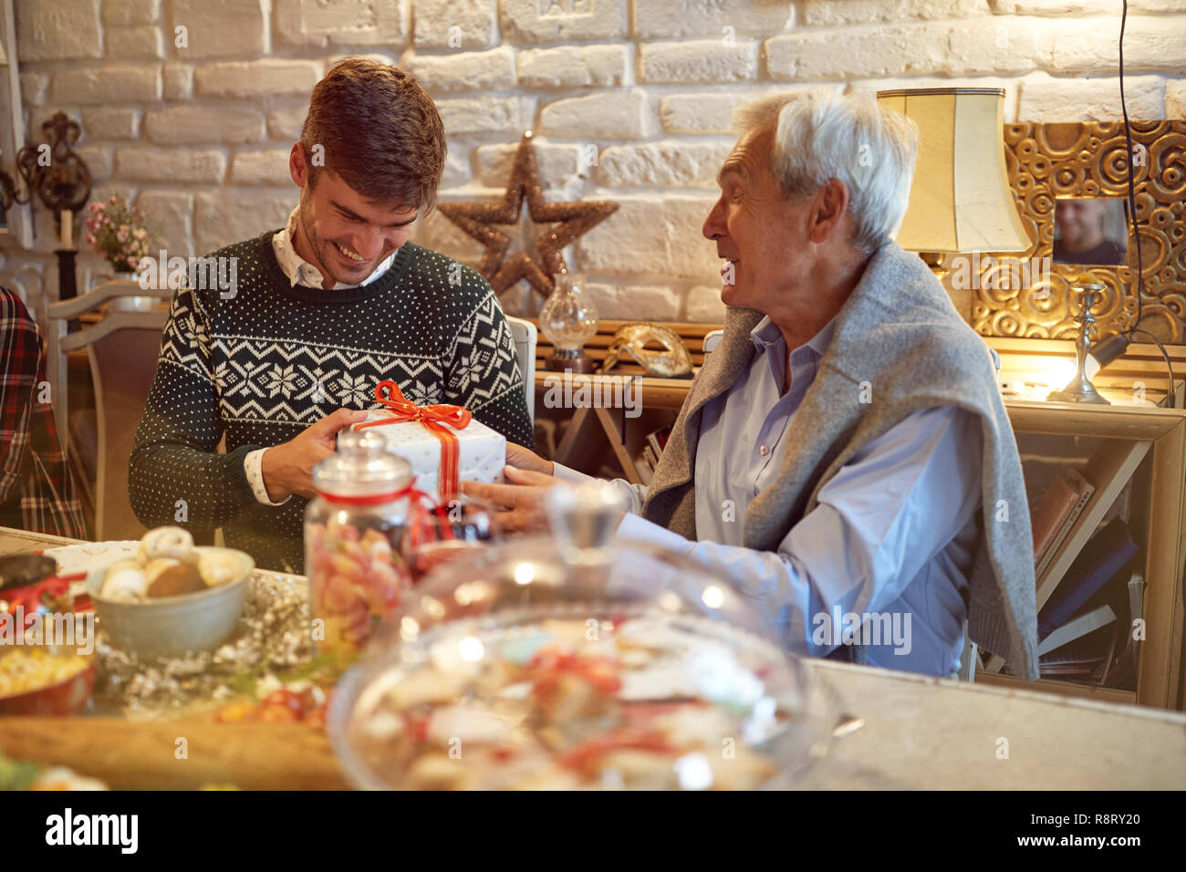 Smiling Son and senior father together celebrate Christmas at home Stock Photo