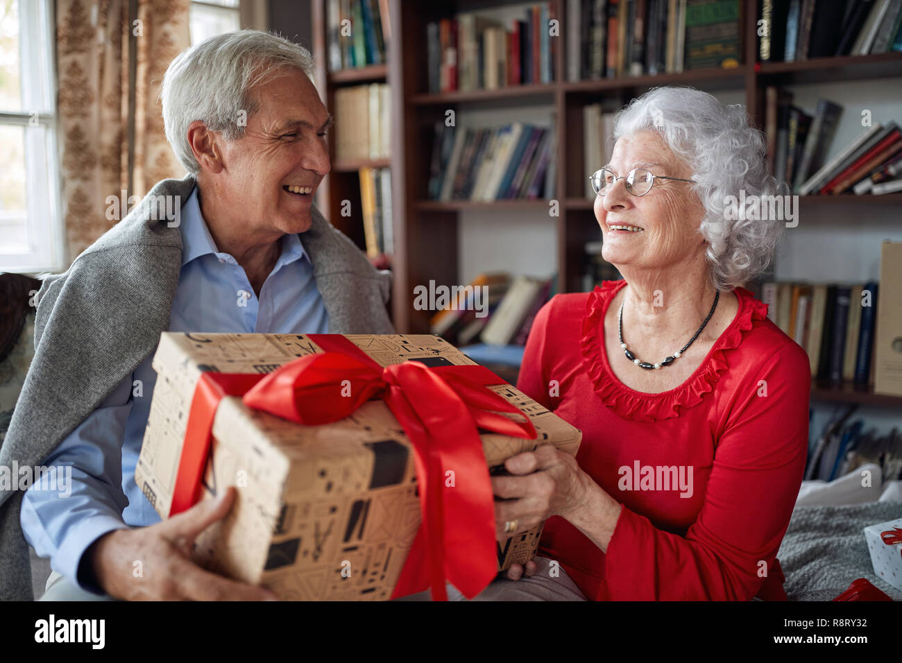 Senior Couple Exchanging Christmas Gifts at Home Stock Photo
