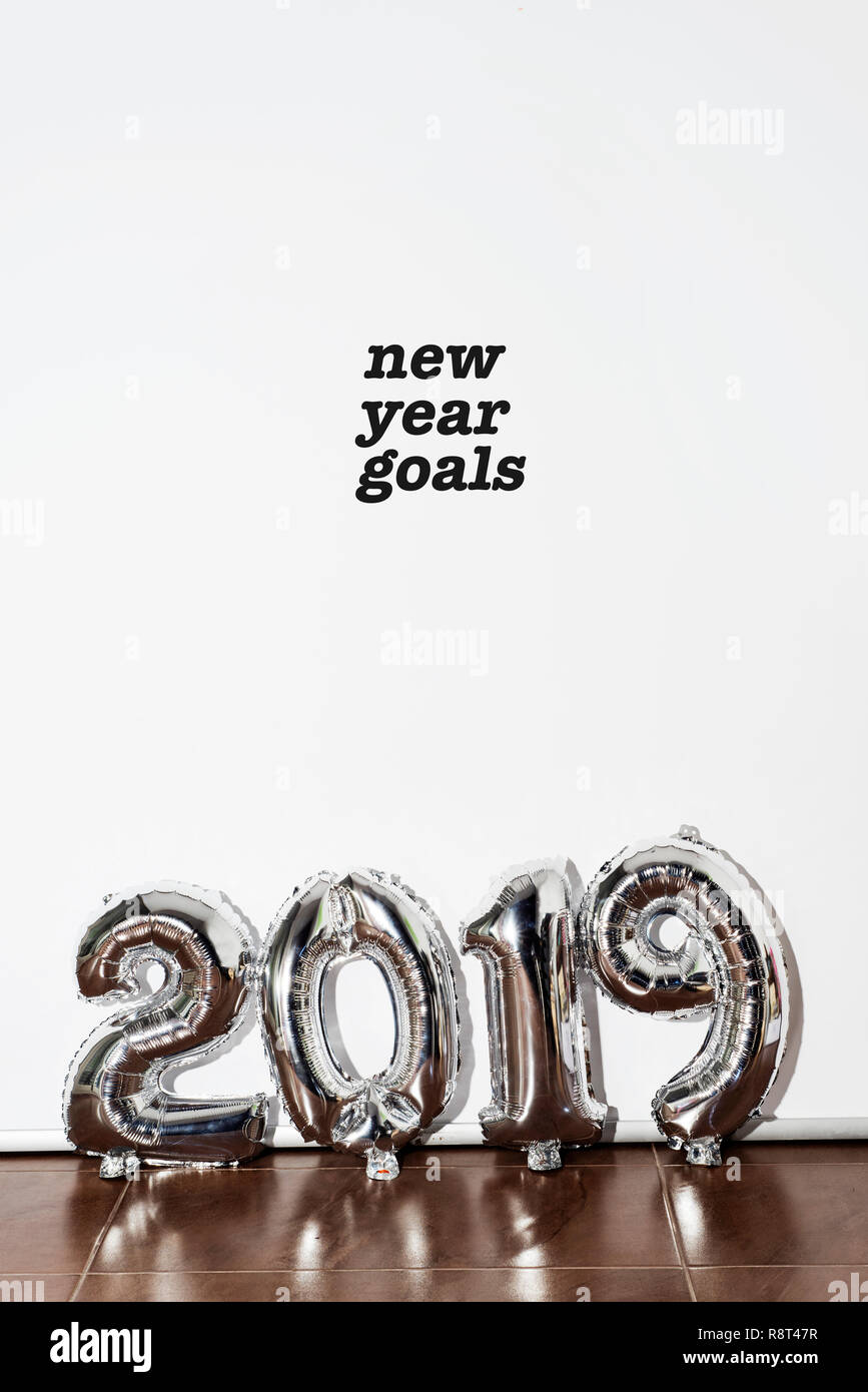 the text new year goals and some silvery number-shaped balloons forming the number 2019 against a white background Stock Photo