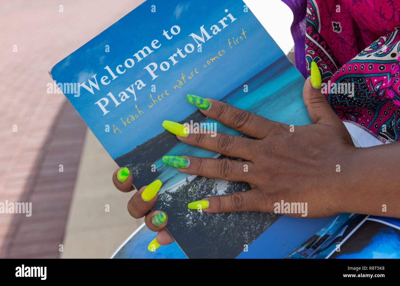 Female hands with long false green and yellow fingernails, Curacao Stock Photo