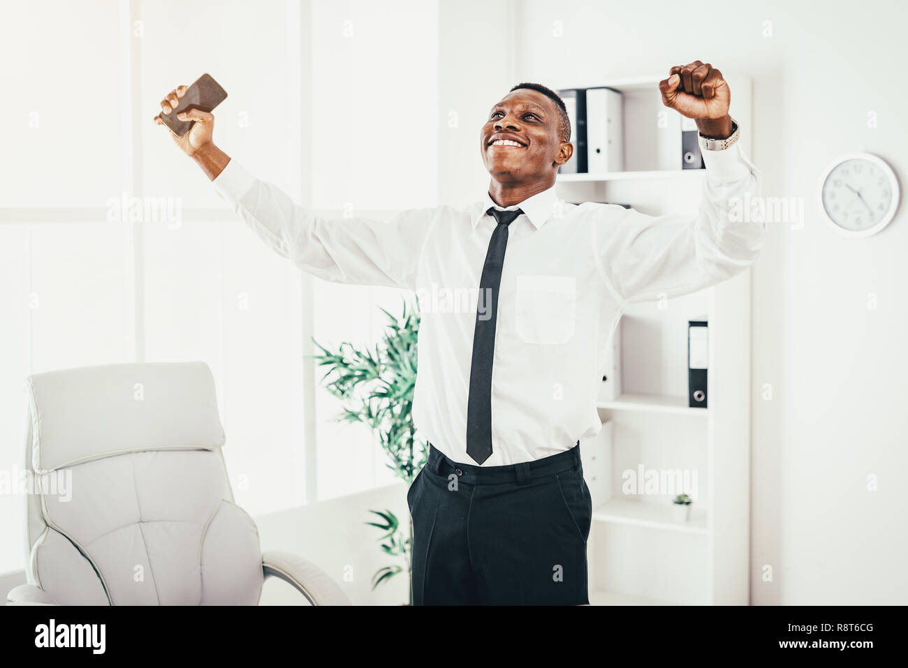 Successful African businessman celebrating success with raised arms in ...
