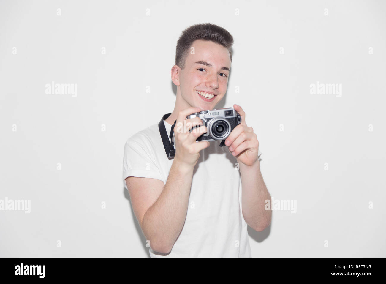 Portrait smiling, confident teenage boy with retro camera Stock Photo