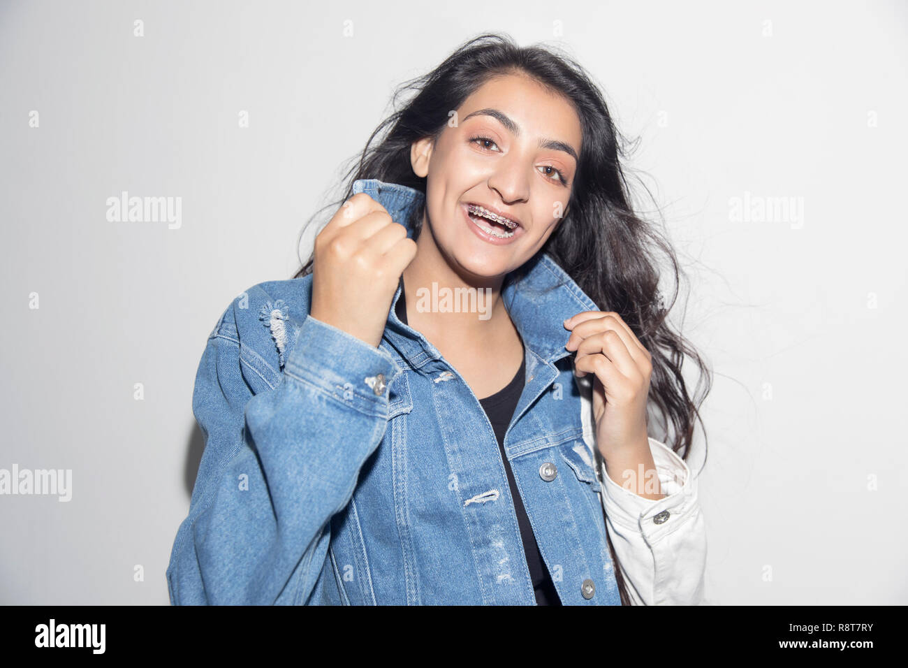 Portrait happy, confident teenage girl with braces wearing denim jacket Stock Photo
