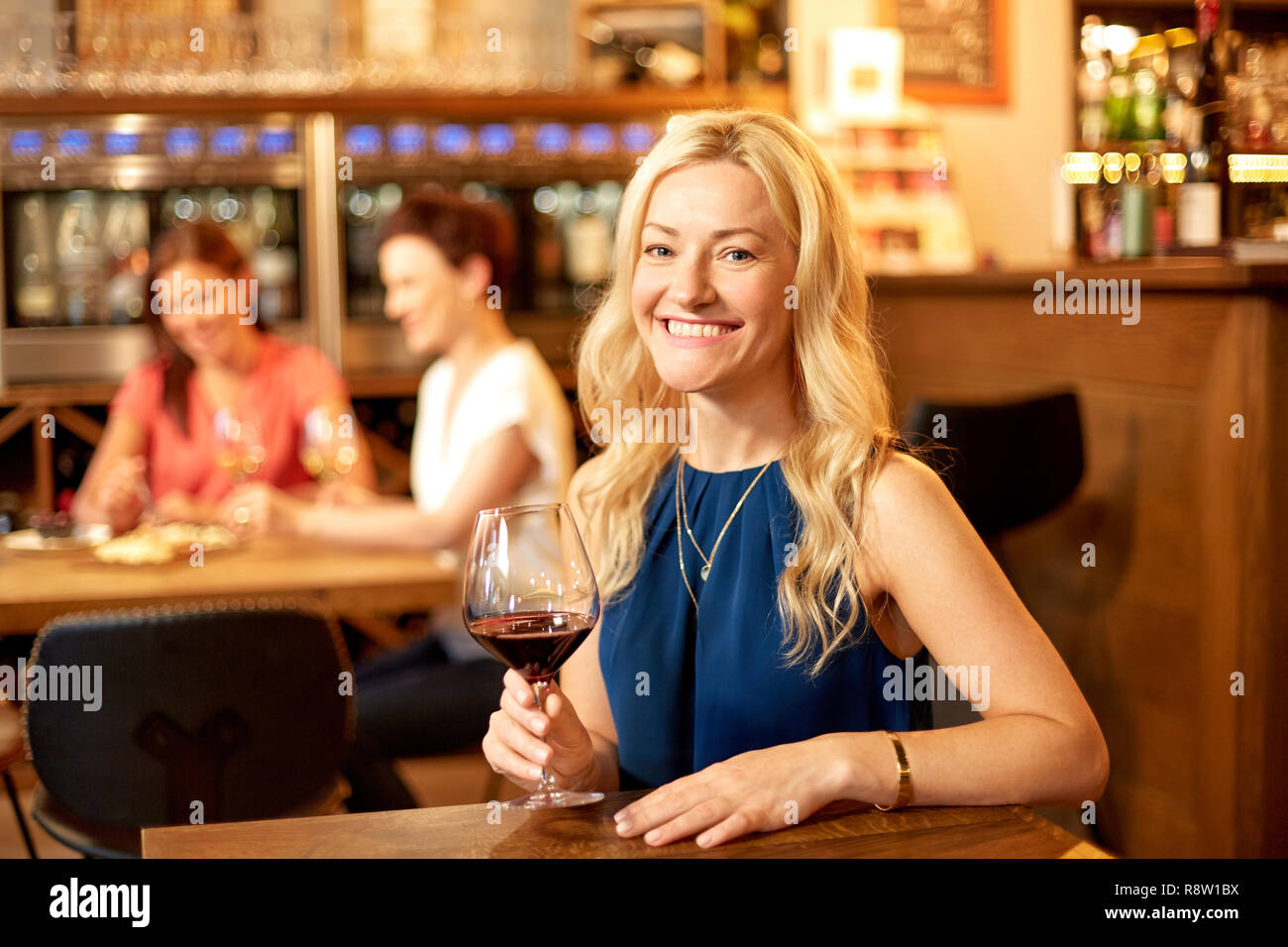happy woman drinking red wine at bar or restaurant Stock Photo
