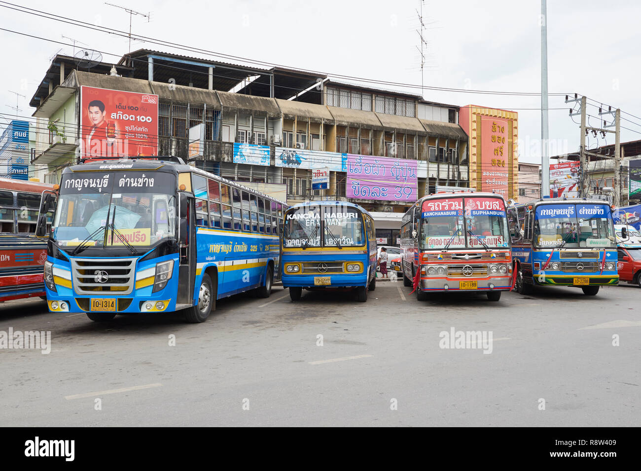 Interurban buses parked at Kanchanaburi central bus terminal, in Thailand. The buses are traditionally very colourful and heavily decorated inside. Stock Photo