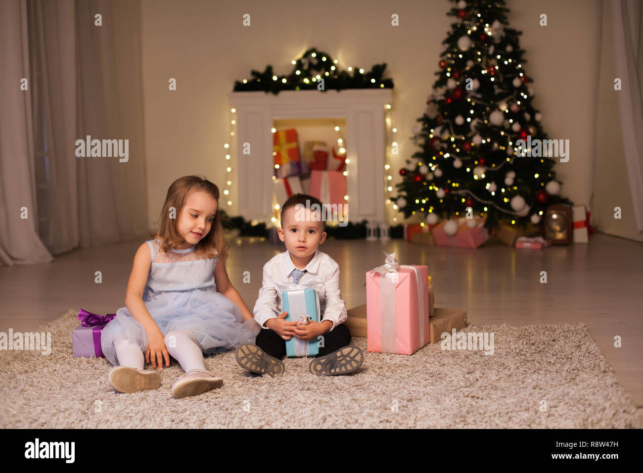 the little boy and girl open Christmas presents Christmas tree new year's Eve family celebration Stock Photo