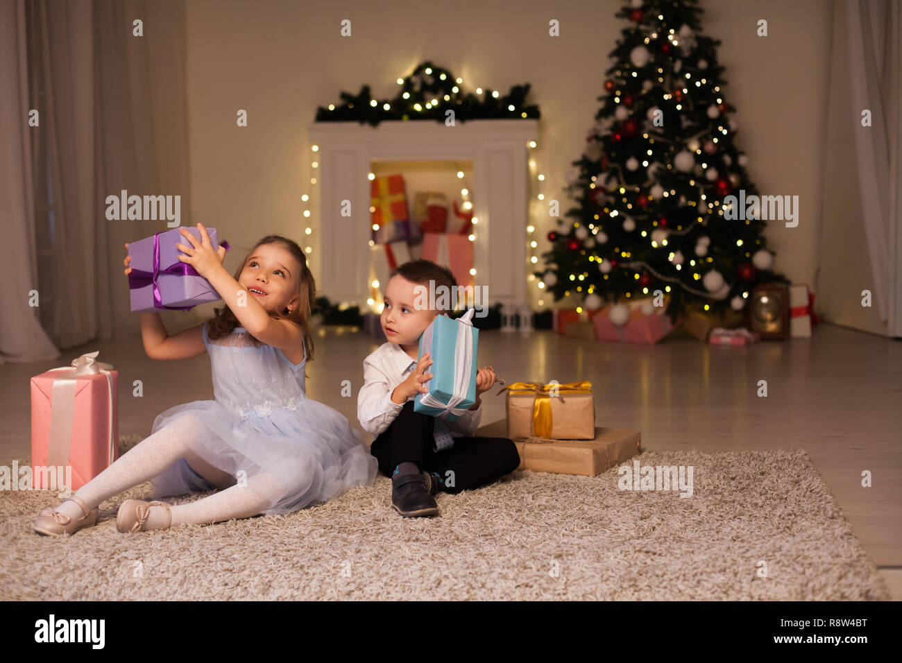 the little boy and girl open Christmas presents Christmas tree new year's Eve family celebration Stock Photo