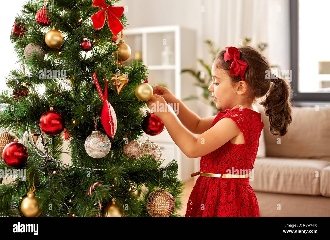 little girl decorating christmas tree at home Stock Photo - Alamy