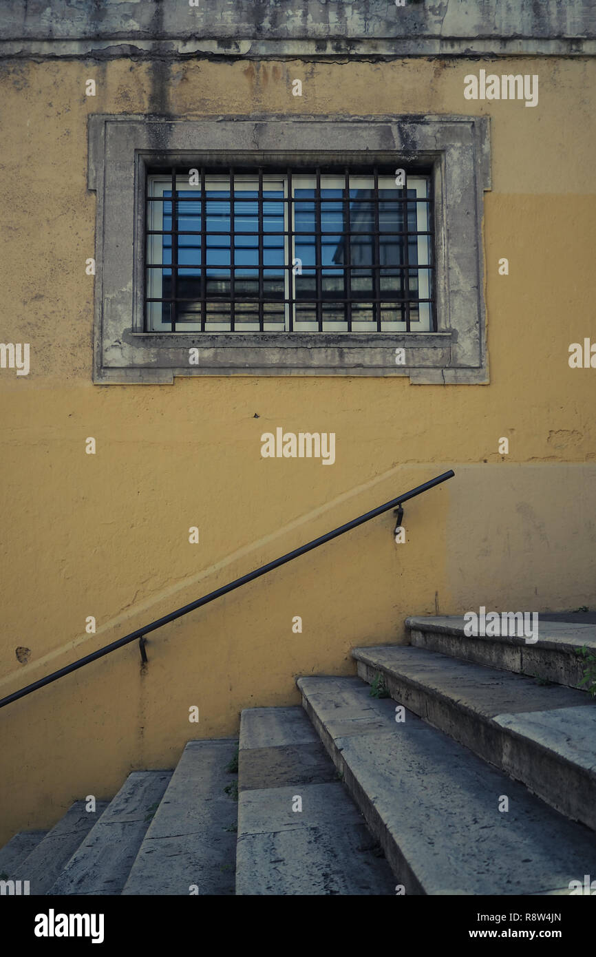 Rome, Italy, window with metal bars along a stone stairway and yellow