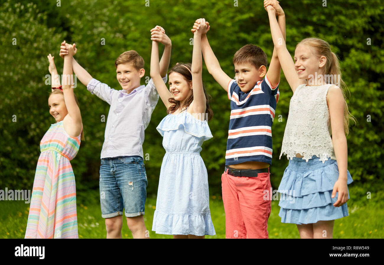happy kids holding raised hands in summer park Stock Photo - Alamy