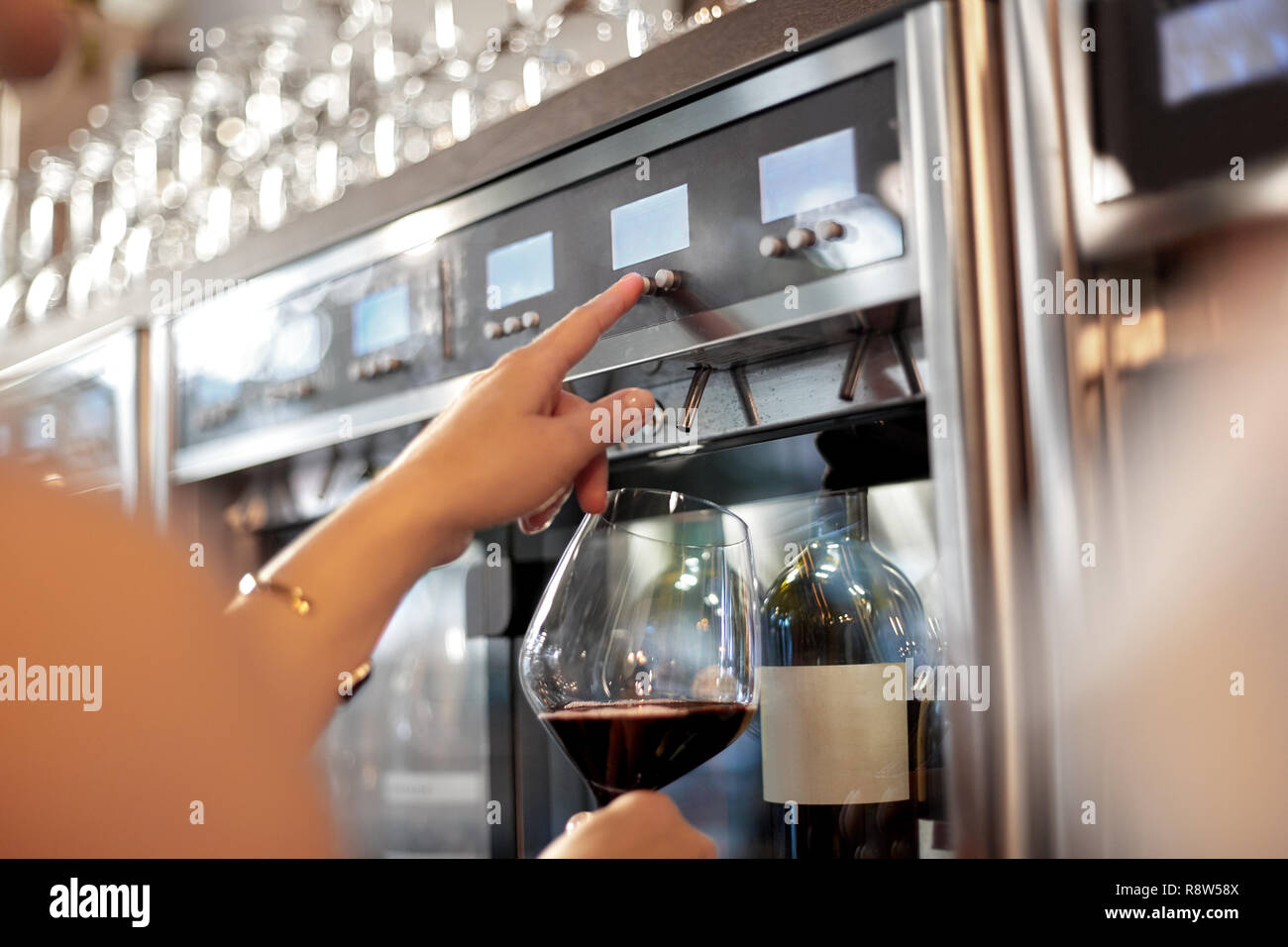 close up of woman with glass at wine dispenser Stock Photo