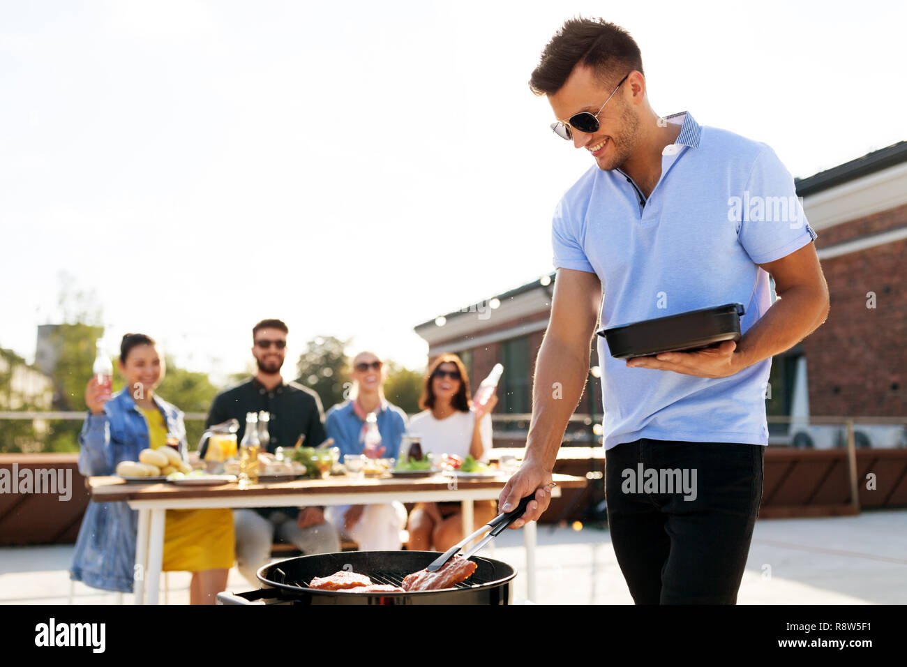man cooking meat on bbq at rooftop party Stock Photo Alamy