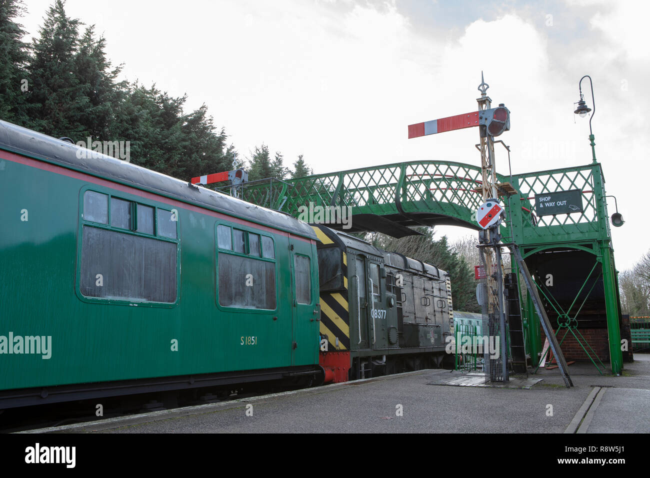 Low angle view of a diesel engine on retro railway. Rolling stock stopped at signal on a platform under a footbridge. Stock Photo