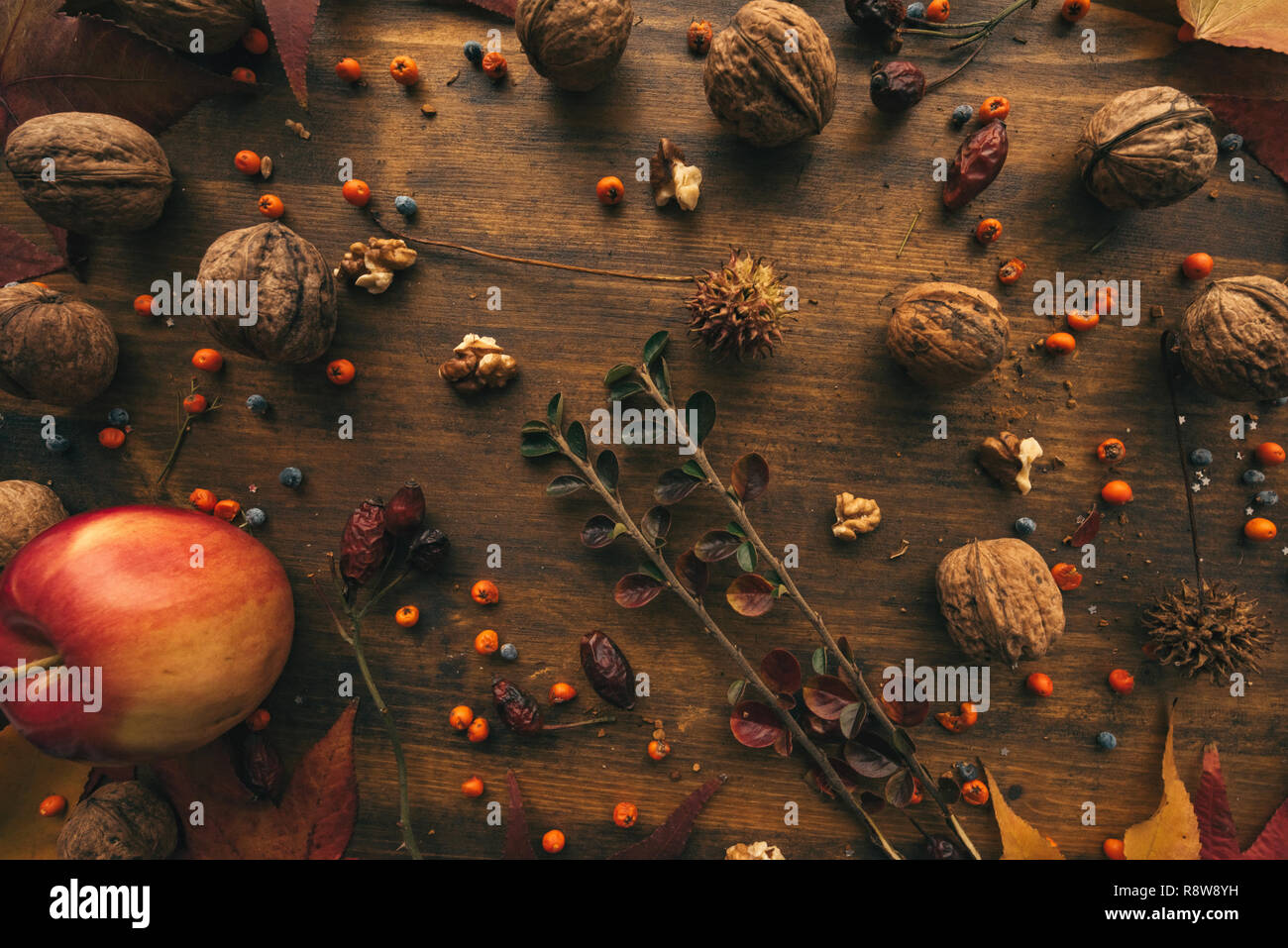 Rustic top view flat lay autumn arrangement decoration with some fruit and dry maple leaves on wooden table Stock Photo