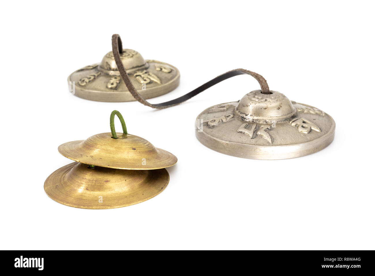 Silver Tibetan tingsha - two cymbals tied with a leather strap and Indian finger cymbals with green rubber handle Stock Photo