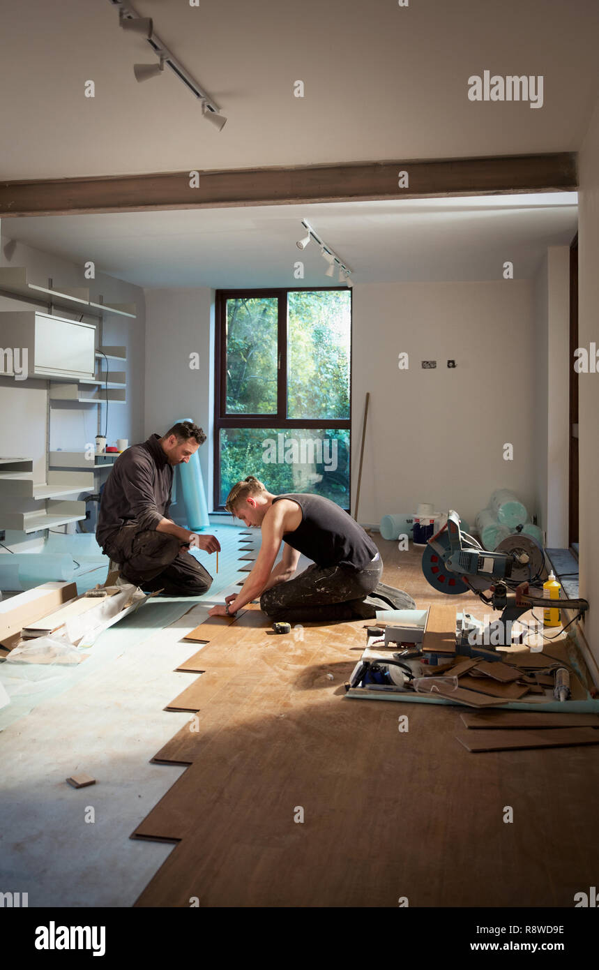 Construction workers laying hardwood flooring in house Stock Photo