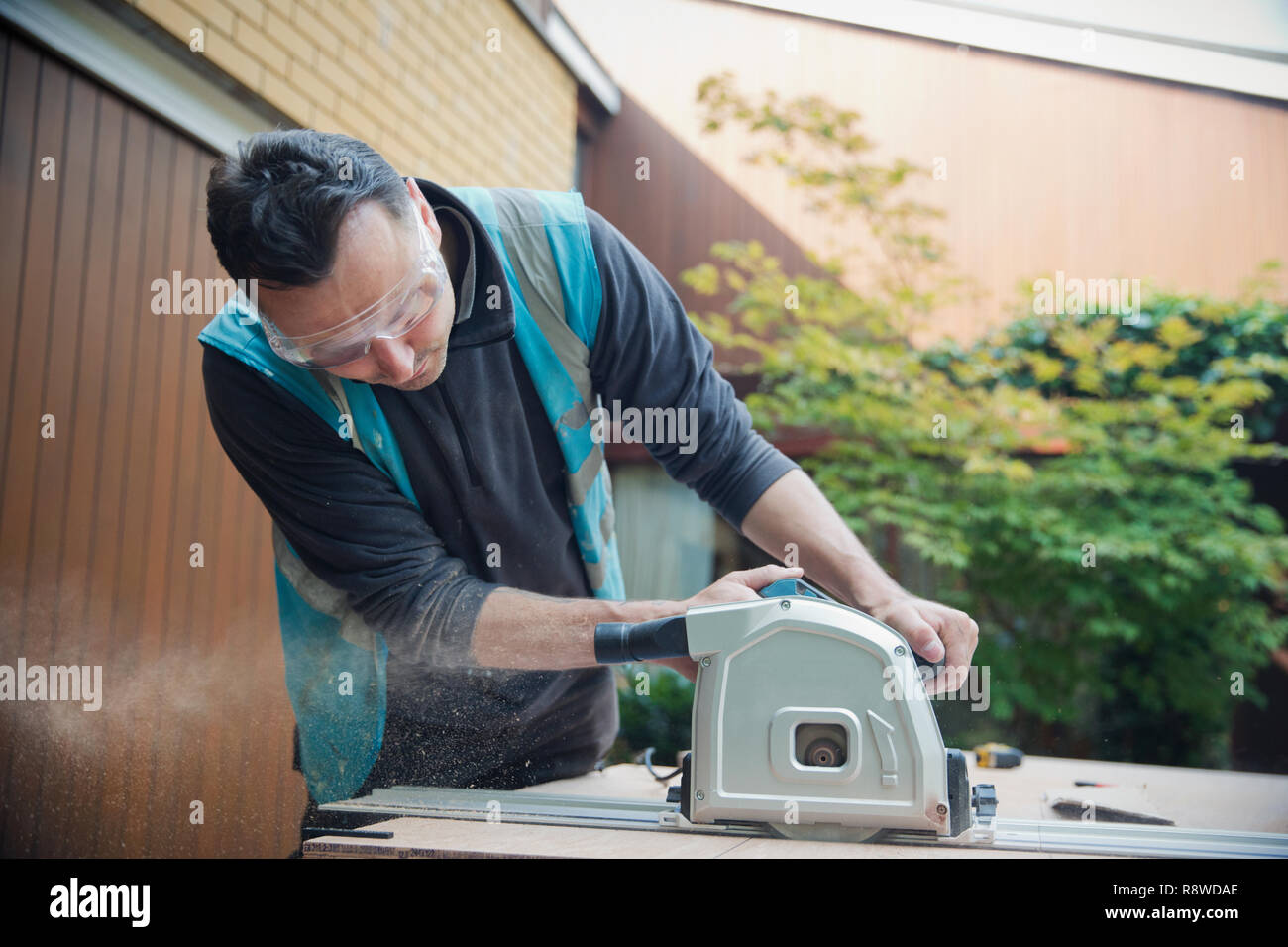 Construction worker using table saw in driveway Stock Photo