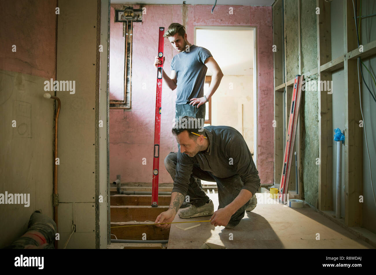 Construction workers using tape measure and level tool in house Stock Photo