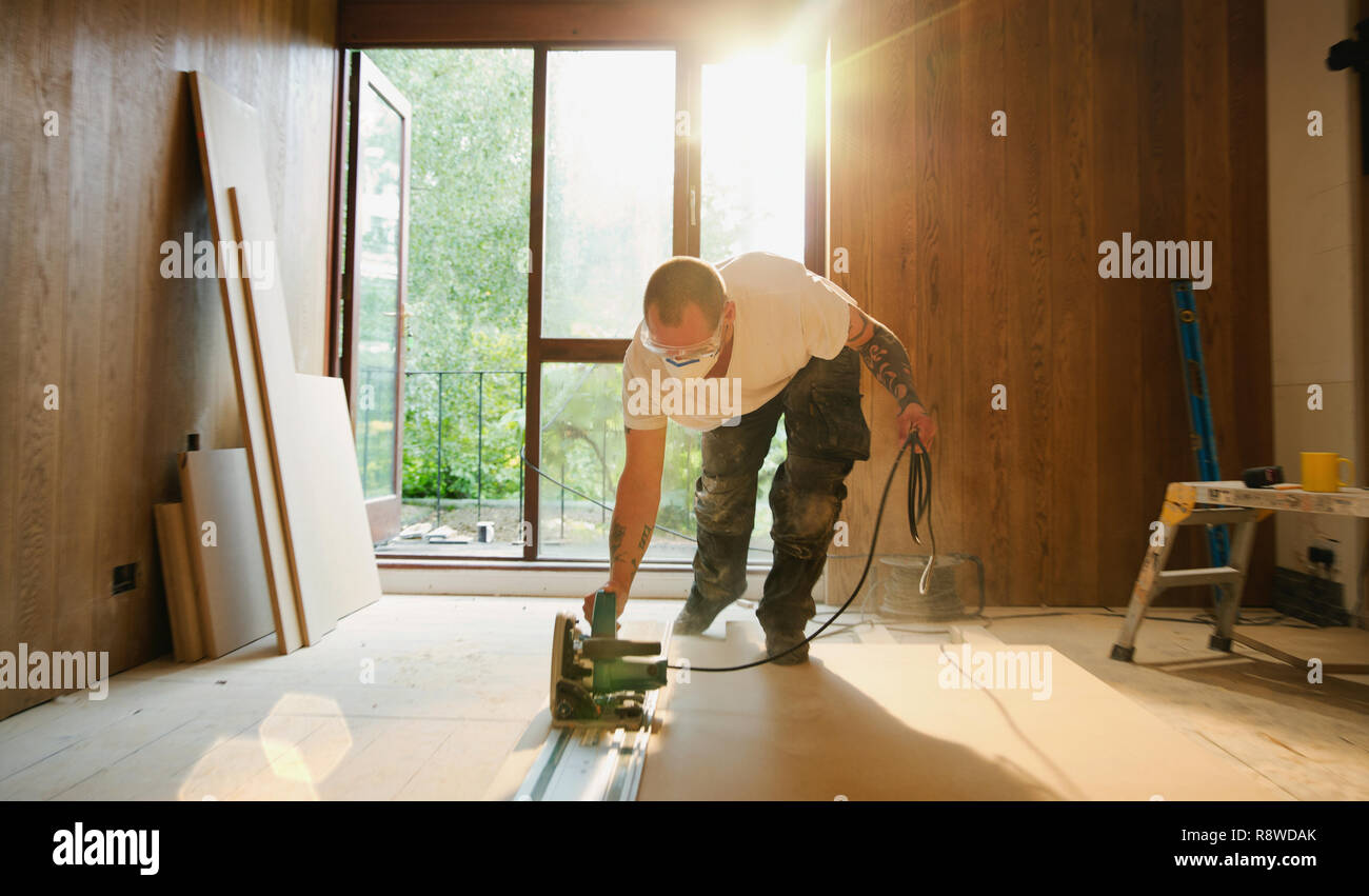 Construction worker using electric saw to cut wood in house Stock Photo